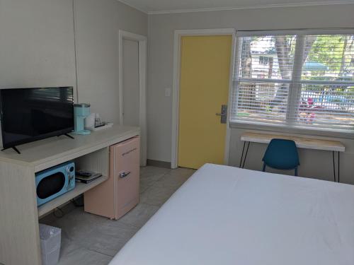 a room with a tv and a desk with a microwave at Queen's Court Inn in Saint Simons Island