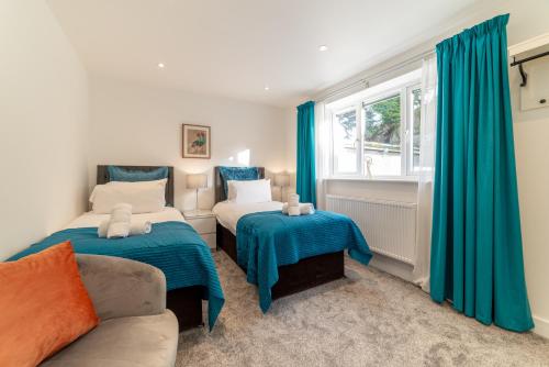 two beds in a room with blue curtains and a couch at Llanberis Lodges in Llanberis