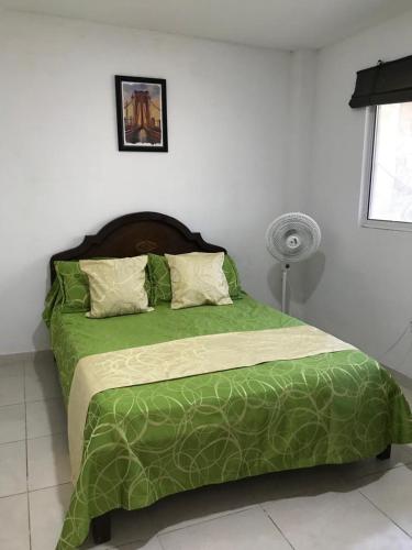 a bed with a green comforter in a bedroom at Cabaña La Blanquita in San Bernardo del Viento
