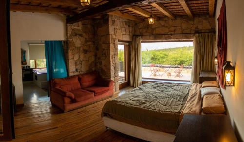 a bedroom with a bed and a couch and a window at Costas del Cuniputu - Casa de Campo in Capilla del Monte