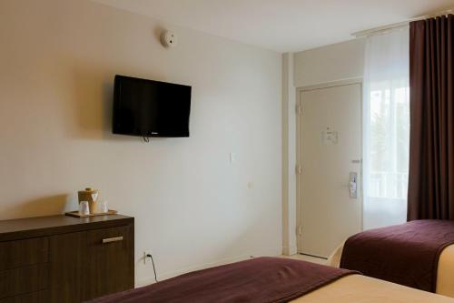 a hotel room with two beds and a television on the wall at Collins Hotel in Miami Beach
