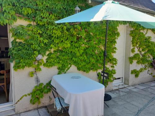 une table et un parasol devant un mur dans l'établissement Maison de Marie, à Bléré