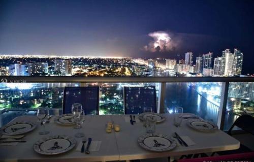 a dining table with a view of a city at night at Stunning Penthouse Suite Waterfront 2BD 2BA in Hallandale Beach