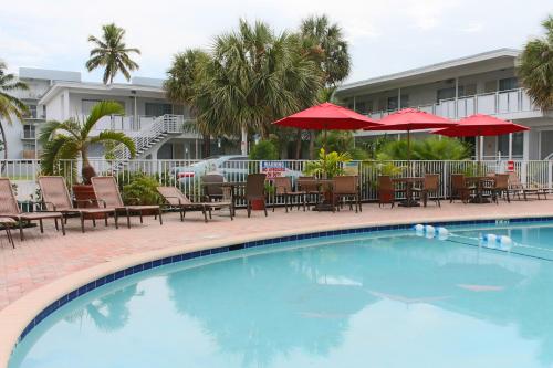 einen Pool mit Tischen, Stühlen und Sonnenschirmen in der Unterkunft Collins Hotel in Miami Beach