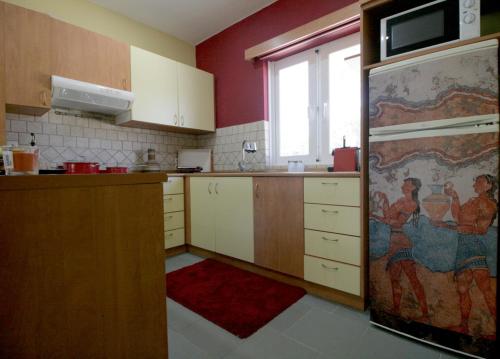 a kitchen with white cabinets and a refrigerator with a window at Seaside, relaxing family house with playground! Villa Lavrys 3 in Marathi