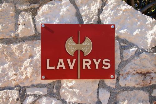 a red sign on a rock with the logo of lawneys at Seaside, relaxing family house with playground! Villa Lavrys 3 in Marathi
