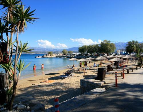 a beach with umbrellas and people in the water at Seaside, relaxing family house with playground! Villa Lavrys 3 in Marathi