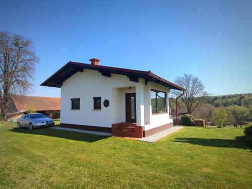 una pequeña casa blanca con un coche aparcado en un patio en APARTMA KAPELSKI FANT, en Sveti Jurij ob Ščavnici