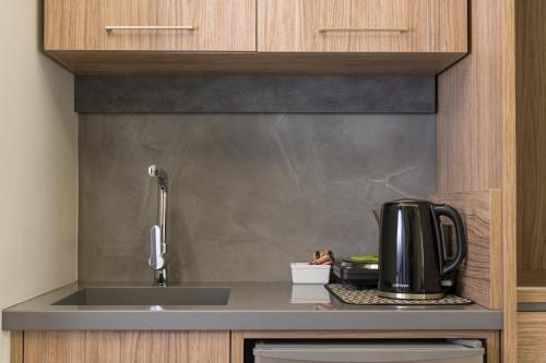 a kitchen with a sink and a coffee maker on a counter at Alkionides Seaside Hotel in Plataniás