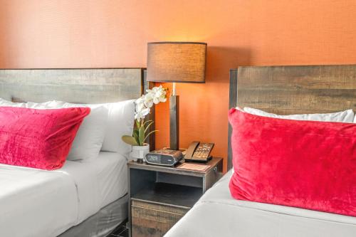 two beds with red pillows in a hotel room at The Fairwind Hotel in Miami Beach