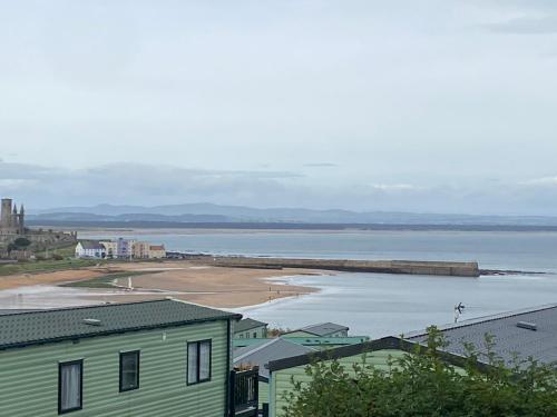 a view of a beach with a house and the water at St Andrews Holiday Home Walk to the Old Course in St. Andrews