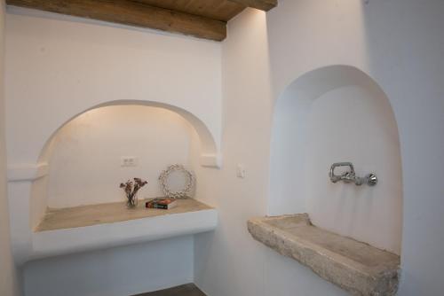 New Apartment in the heart of Mykonos town - 2 في مدينة ميكونوس: حمام بجدران بيضاء ورف مع حوض