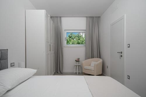a white bedroom with a white bed and a chair at Perla Luxury Apartment in Vodice