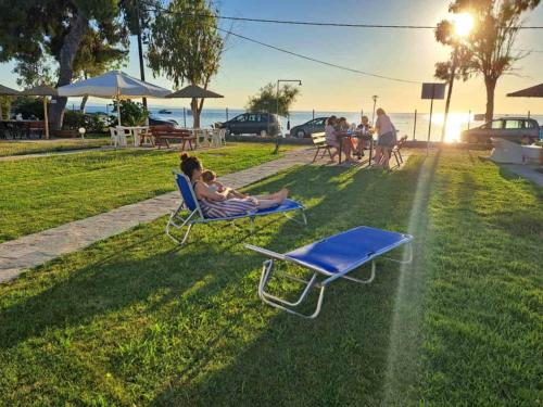 a group of people sitting in lounge chairs on the grass at Dimitra's Family Apartments 2 in Paradisos