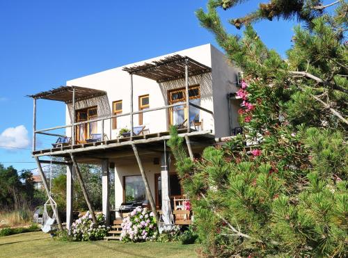 una casa con balcón y flores en el patio en Hale Lau, en José Ignacio