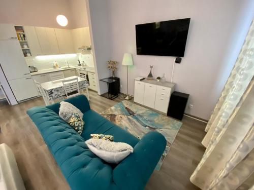 a living room with a blue couch and a tv at Kings main square Apartment - AC - Balcony - Coffee Machine - Washer - Kitchen- Parking in Poprad