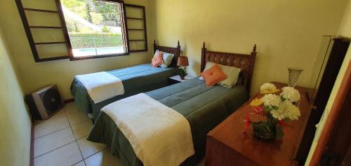 a bedroom with two beds and a table with flowers at Casa Família, piscina, hidro aquecida, cercada in Petrópolis