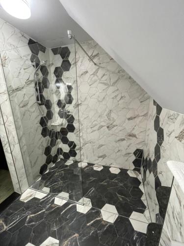 y baño con ducha y azulejos blancos y negros. en Casa Bicăjeanului - Lacu Roșu, en Lacu Roșu