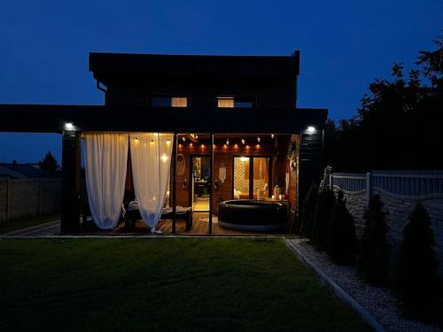 una casa con cortinas blancas en el patio por la noche en my_brooklyn_ DOM Z OSB en Kielce