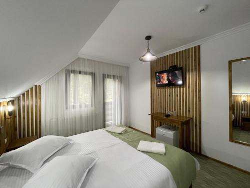 a bedroom with a large white bed and a mirror at Casa Bicăjeanului - Lacu Roșu in Lacu Rosu