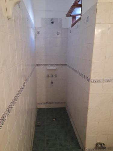 baño pequeño con paredes de azulejos blancos y lavabo en Rent a Room Salta en Salta