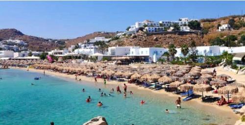 a beach with people in the water and umbrellas at demis Mykonian soul 2 in Platis Gialos
