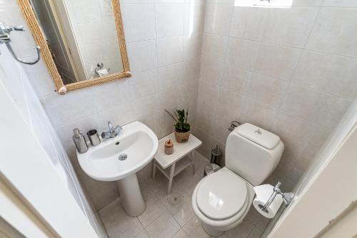 a white bathroom with a toilet and a sink at Casa Francesca in Vrahati