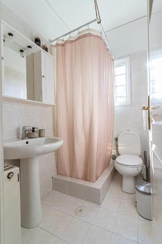 a bathroom with a pink shower curtain and a toilet at Casa Francesca in Vrahati