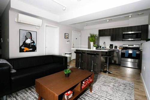 a living room with a black couch and a kitchen at Newly Renovated 2bed, 2bath private apartment, minutes from Boston. in Brookline