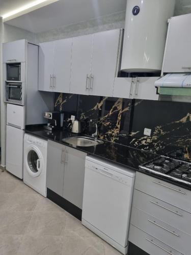 a kitchen with white cabinets and a washer and dryer at Comfors Appartements 2 in Fnidek