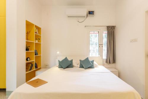 Locul Midtown-Indiranagar في بانغالور: غرفة نوم مع سرير أبيض كبير مع وسائد زرقاء