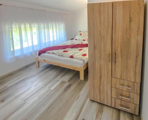 a bedroom with a bed and a wooden cabinet at FeDa Apartmanház in Balatonboglár