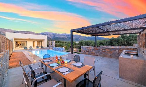 a patio with a table and chairs and a pool at Sissi Lux Villas in Sisi