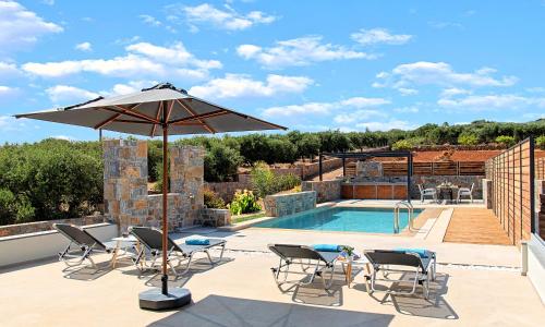 a patio with an umbrella and chairs and a pool at Sissi Lux Villas in Sisi