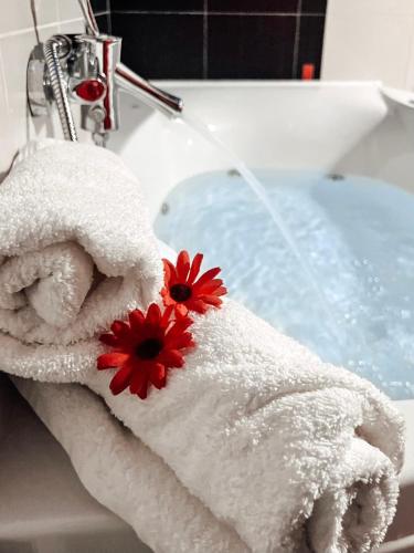 a towel with a red flower on top of a sink at CozyLuxuryApartment in Keramoti