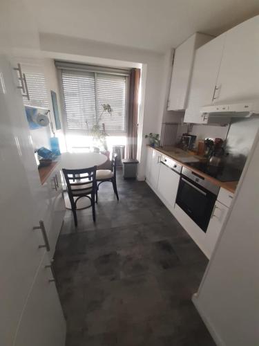 une cuisine avec des armoires blanches et une table et une salle à manger dans l'établissement Parenthèse à Sète, à Sète