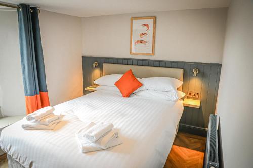a bedroom with a large white bed with orange pillows at Hope and Anchor in Flookburgh