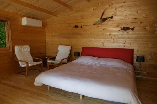 a bedroom with a bed and two chairs and a table at CABANE BAMBOU in Fronsac