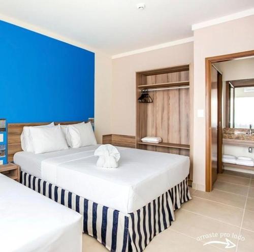 a bedroom with two beds and a blue wall at Apartamento Ondas Praia Resort in Porto Seguro