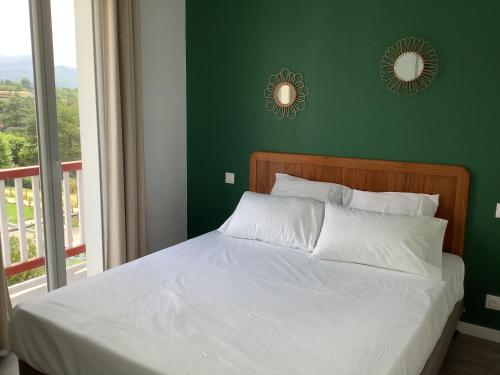 Un dormitorio con una cama blanca con una pared verde. en Trinquet Bordatxo, en San Juan de Luz