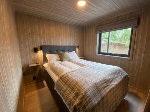 a bed in a small room with a window at Hytte i Sogndal med panoramautsikt in Sogndal