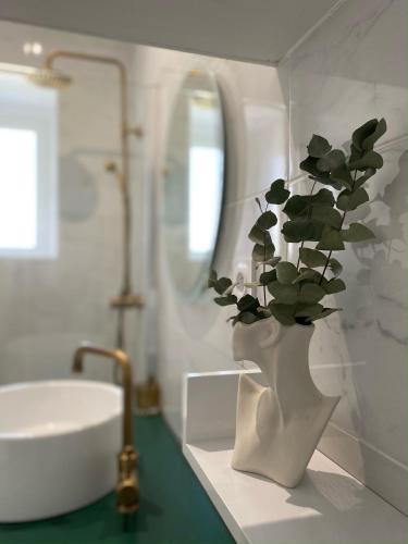 La salle de bains est pourvue d'un lavabo et d'un vase avec une plante. dans l'établissement La Suite Dandy - Beau T2 -Terrasse, Parking gratuit, Climatisation, à Bagnères-de-Bigorre
