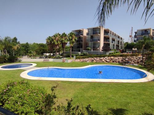 a swimming pool in front of a large building at Paradise Village Port Aventuras in Salou
