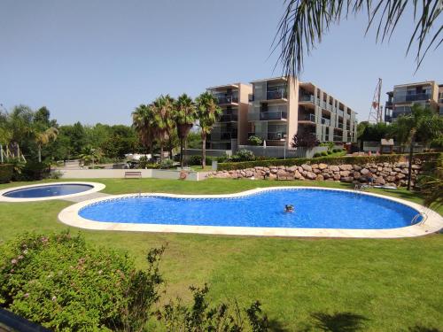 a swimming pool in front of a large building at Paradise Village Port Aventura in Salou