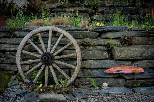 a wooden wagon wheel leaning against a stone wall at Pencarrow Boutique Lodge in Queenstown
