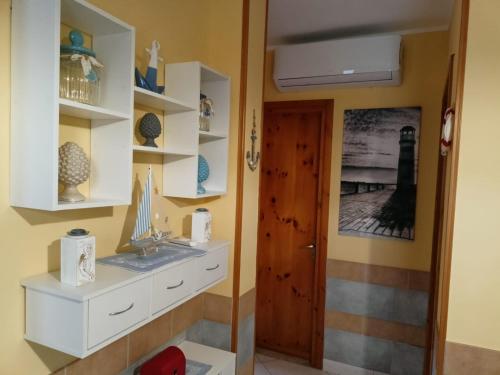 una stanza con lavandino, scaffali e porta di Villetta "Poesia" a 50 m dal mare con giardino e parking a Torre dell'Orso