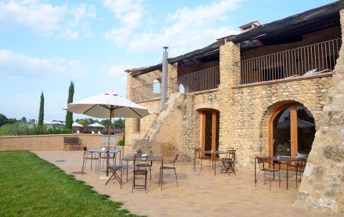 a patio with tables and chairs and an umbrella at Casa Anamaria Hotel in Ollers