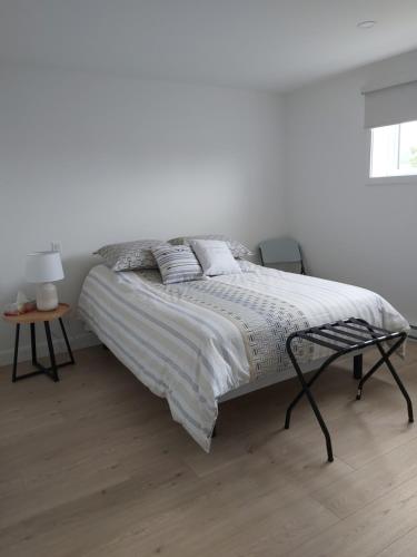 uma cama num quarto branco com uma parede branca em Gîte du 149 route de la Mer em Sainte-Flavie