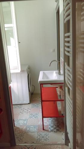 La salle de bains est pourvue d'un lavabo et d'une armoire rouge. dans l'établissement Loches : gîte de charme indépendant avec jardin, à Loches