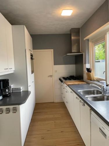 a kitchen with white cabinets and a sink at HolidayHome Zonnestraal 9p Amsterdam and the beach in Heerhugowaard